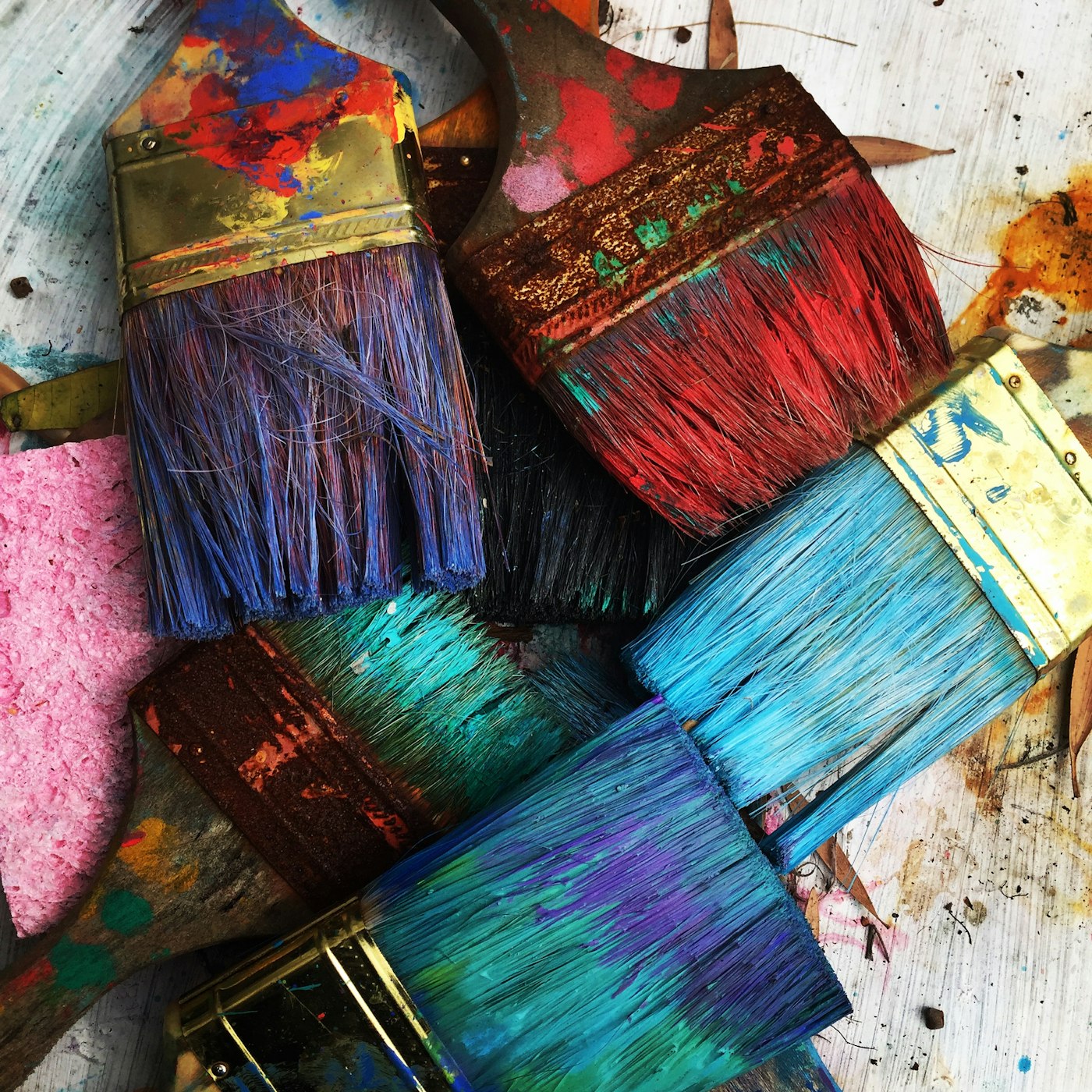 A pile of well-used paintbrushes loaded with colorful paint.